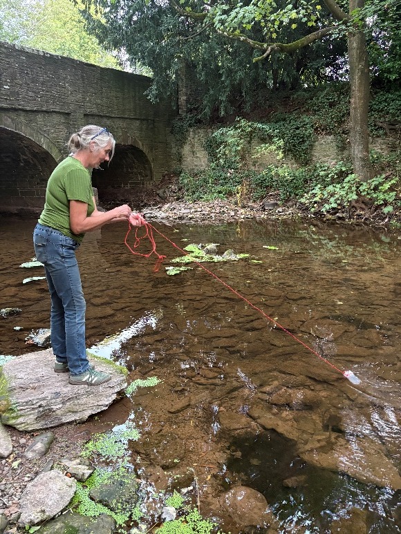 Taking a water sample from the River Dore beside a stone bridge